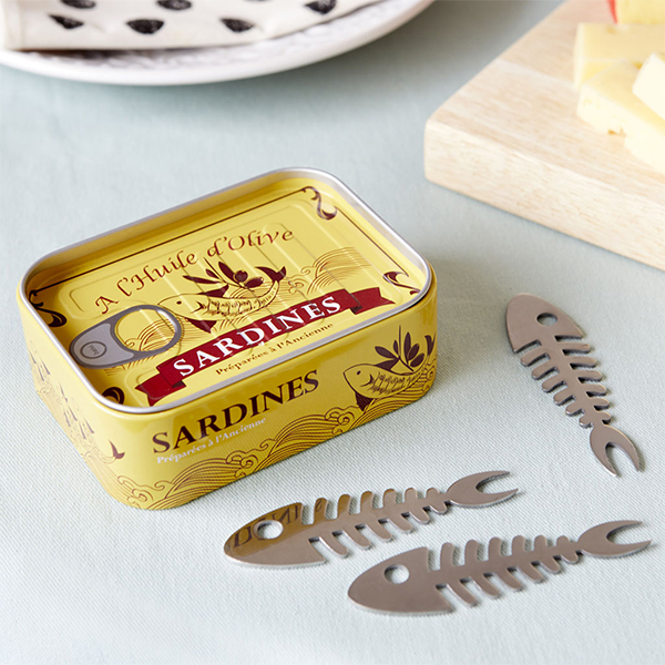 Boîte de sardine avec des pics apéritif en forme d'arête de poisson posée sur une table