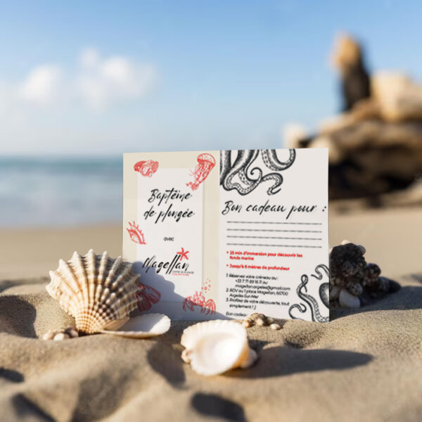 Bon cadeau baptême de plongée sous forme de carte plantée dans le sable sur une plage